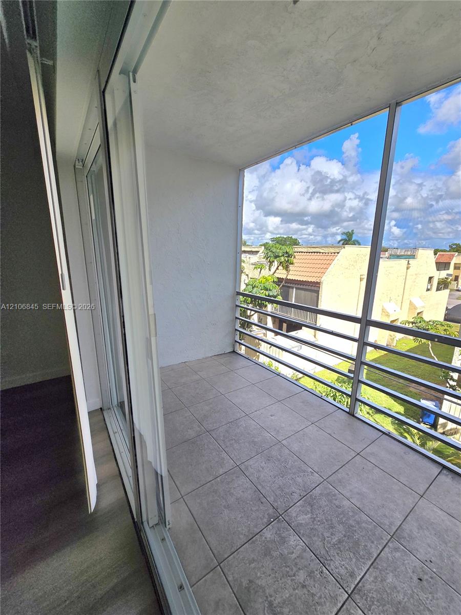 Covered balcony featuring tile flooring, aluminum screen enclosure, and sliding glass door access