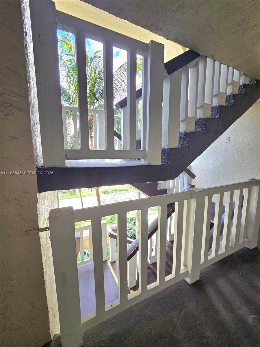 Exterior staircase featuring white vertical slat railings, concrete steps, and a dark-toned structural stringer