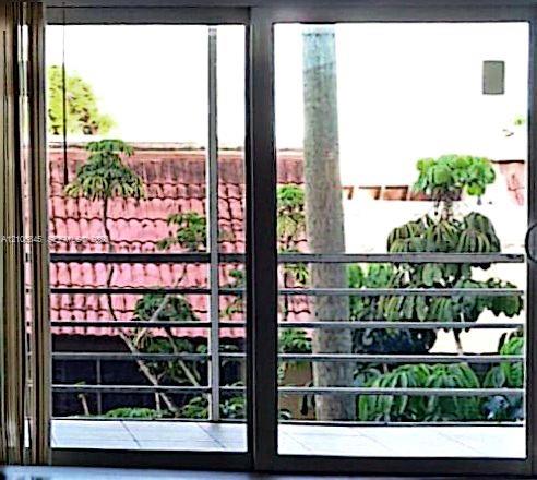 Sliding glass door featuring a metal frame, opening to a tiled balcony with horizontal metal railings