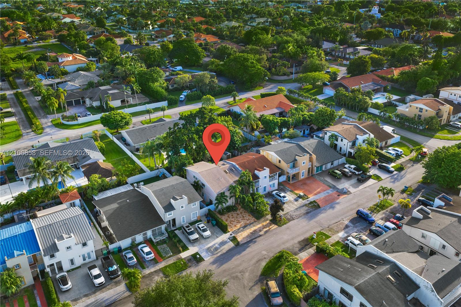 Aerial view of property featuring a paved driveway, tile roofing, and landscaped perimeter