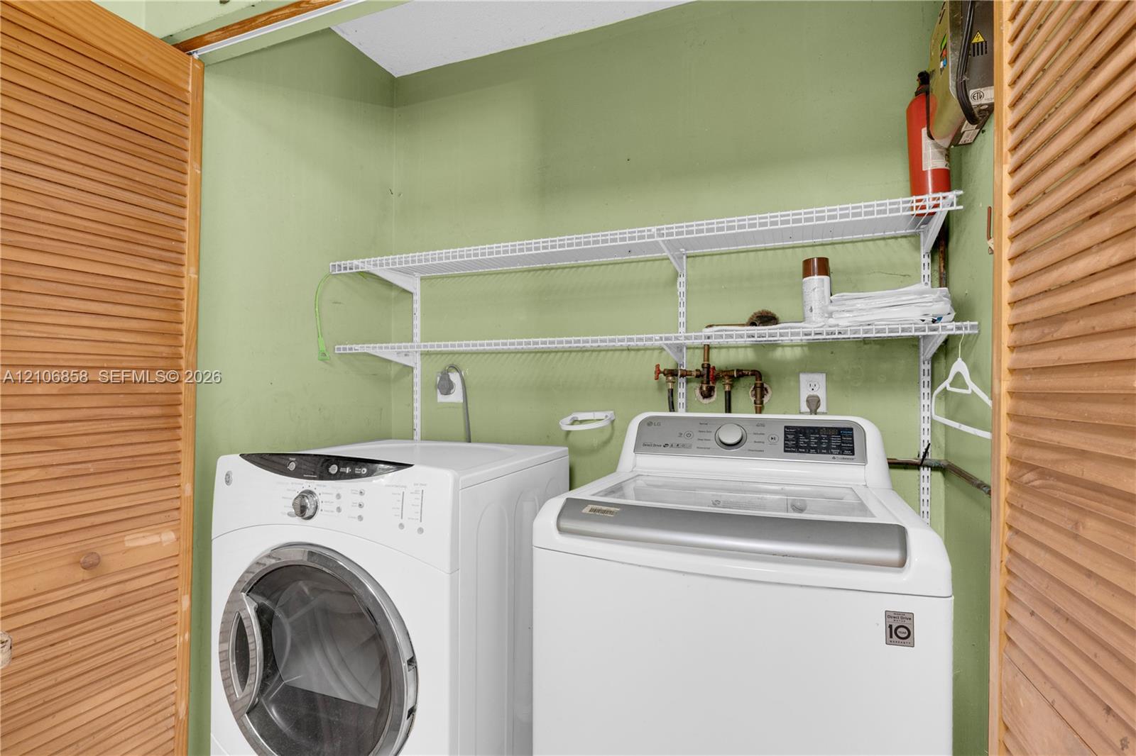 Laundry area featuring dual louvered wood doors and two-tier wire shelving