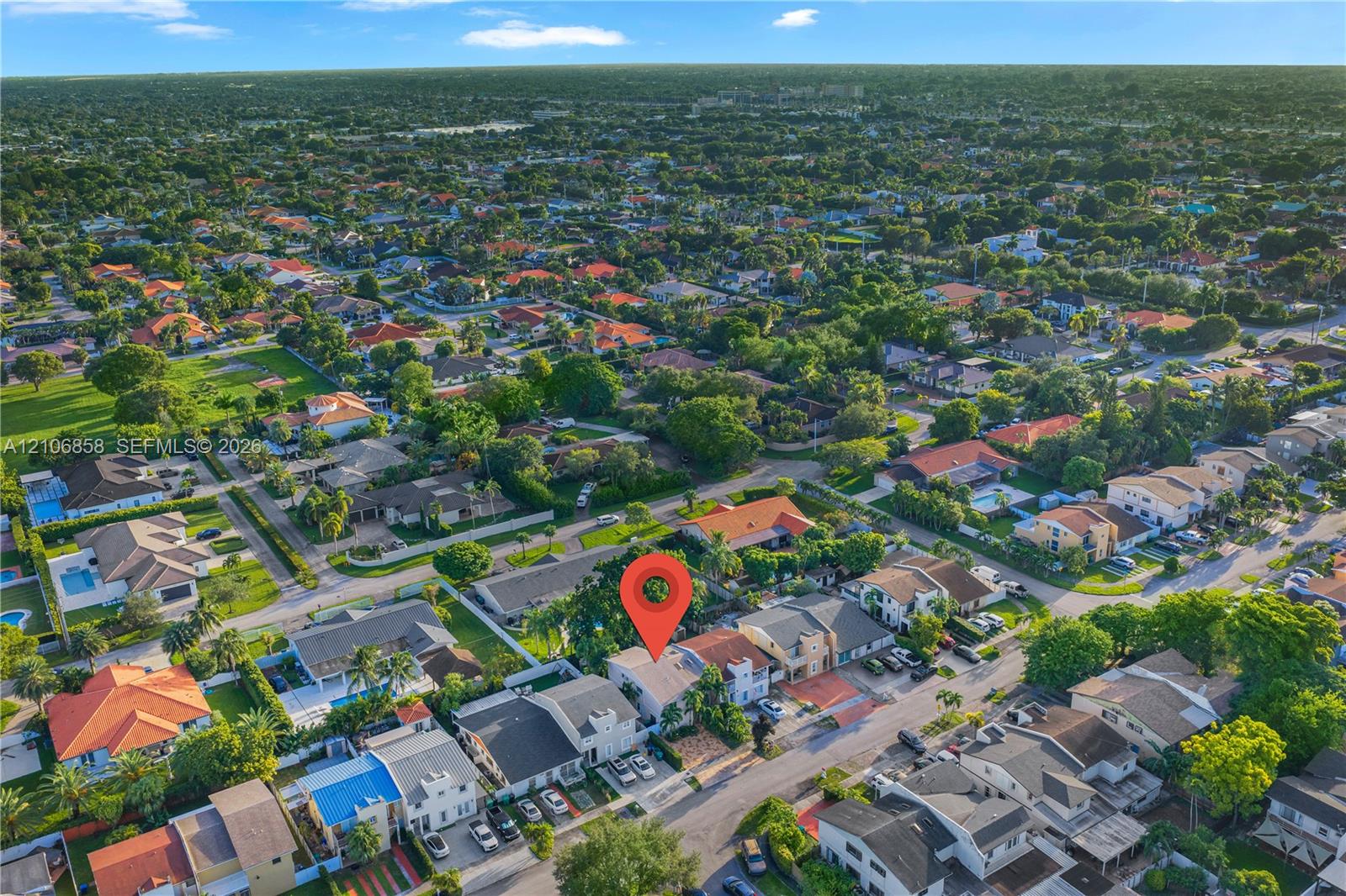 Aerial perspective of a residential property featuring a paved driveway, multi-level roofline, and mature landscaping