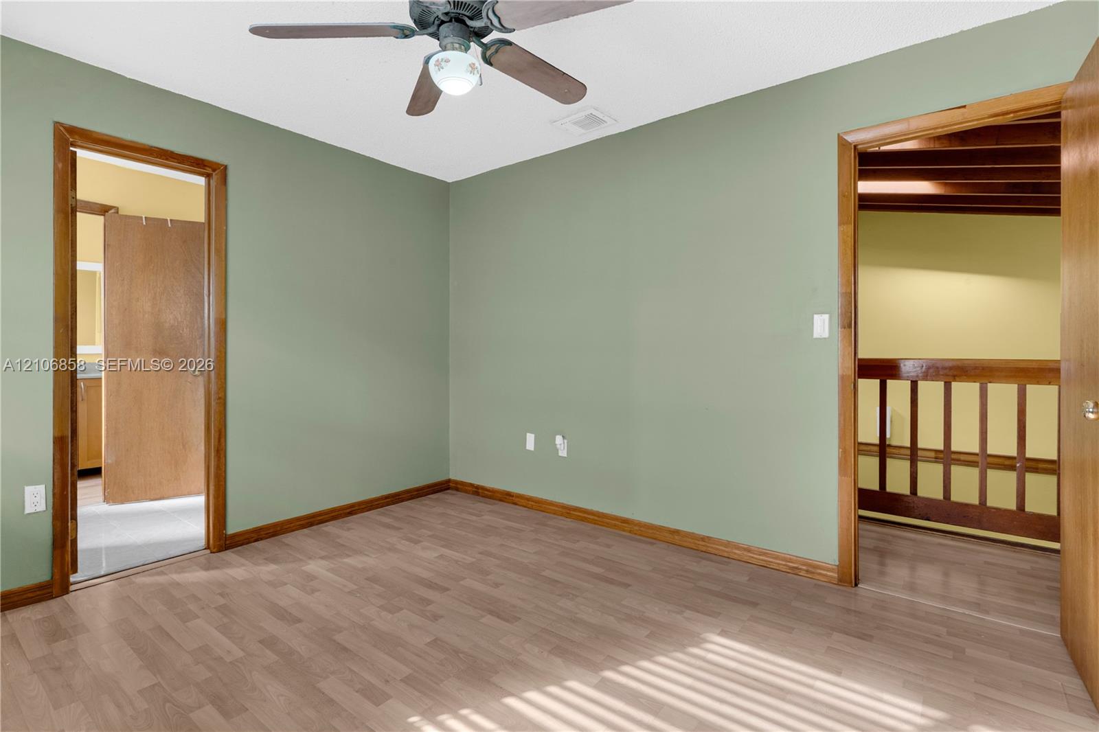 Interior room featuring wood-finish flooring, a ceiling fan with integrated lighting, and wooden door trim