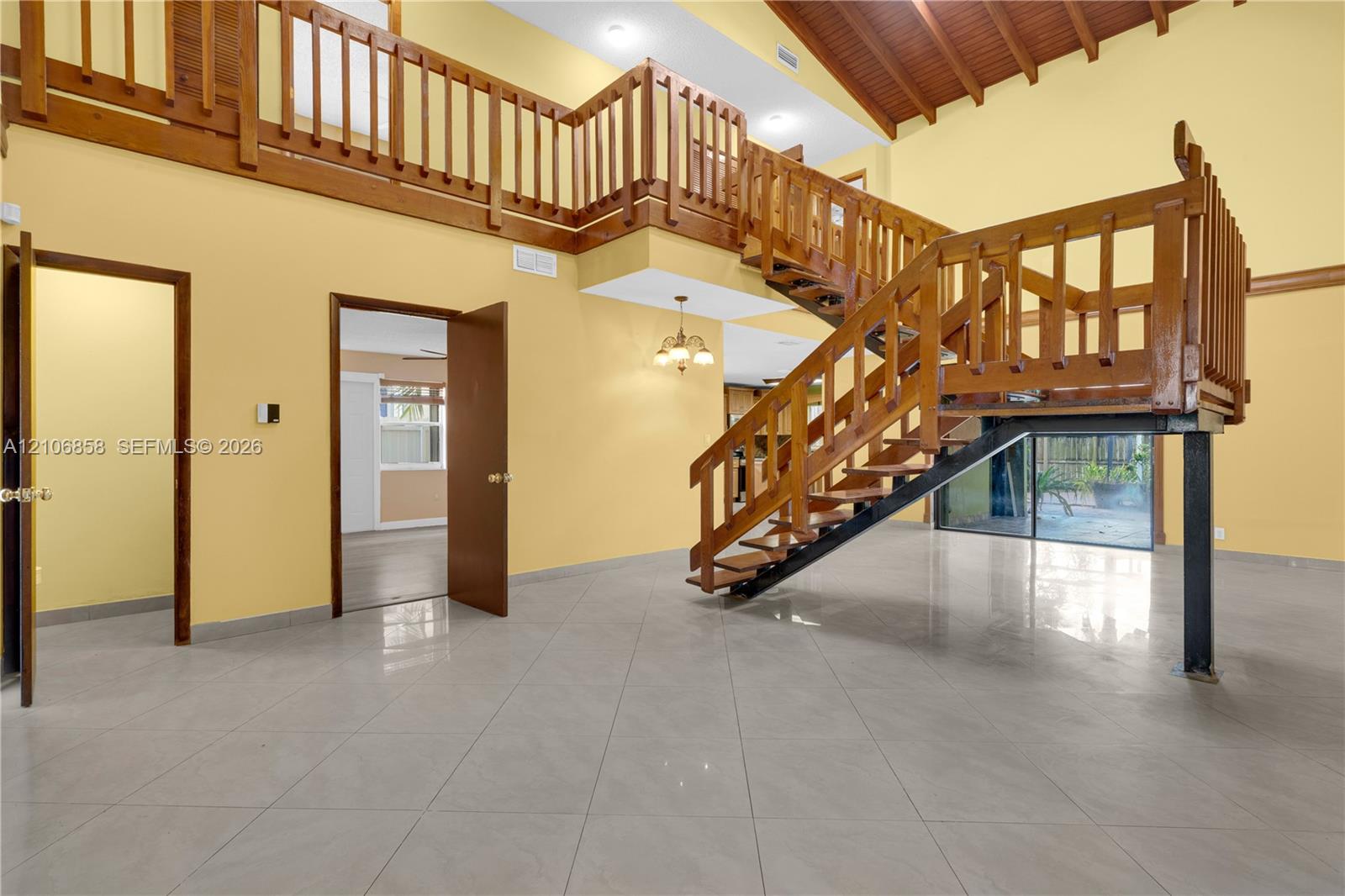 Vaulted ceilings with exposed wooden beams, tile flooring, and a multi-level wooden staircase with balustrade railings Vaulted ceilings with exposed wooden beams, tile flooring, and a multi-level wooden staircase with balustrade railings