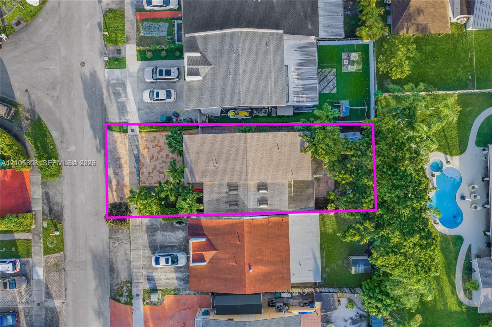 Aerial perspective showcasing a parcel featuring a paved front courtyard, gable roofline, and mature landscaping