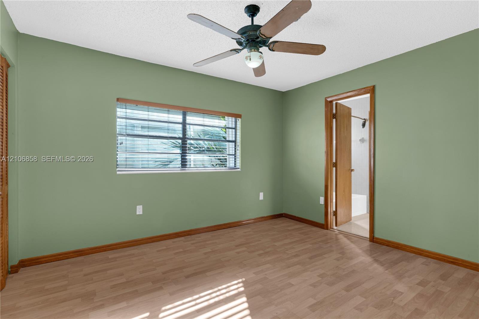 Interior space featuring wood-finish flooring, a multi-blade ceiling fan, and window with integrated blinds