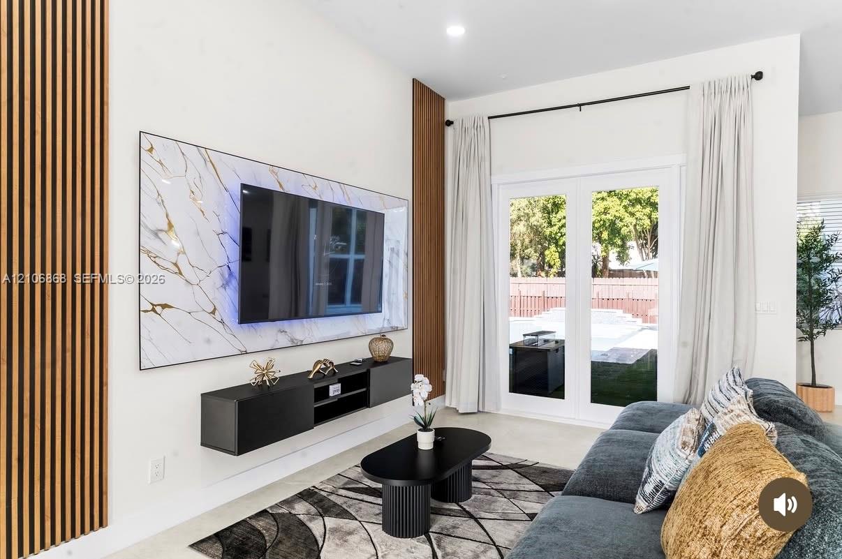 Living area featuring vertical slat wood wall paneling, a large stone-finish media wall, and a floating black console