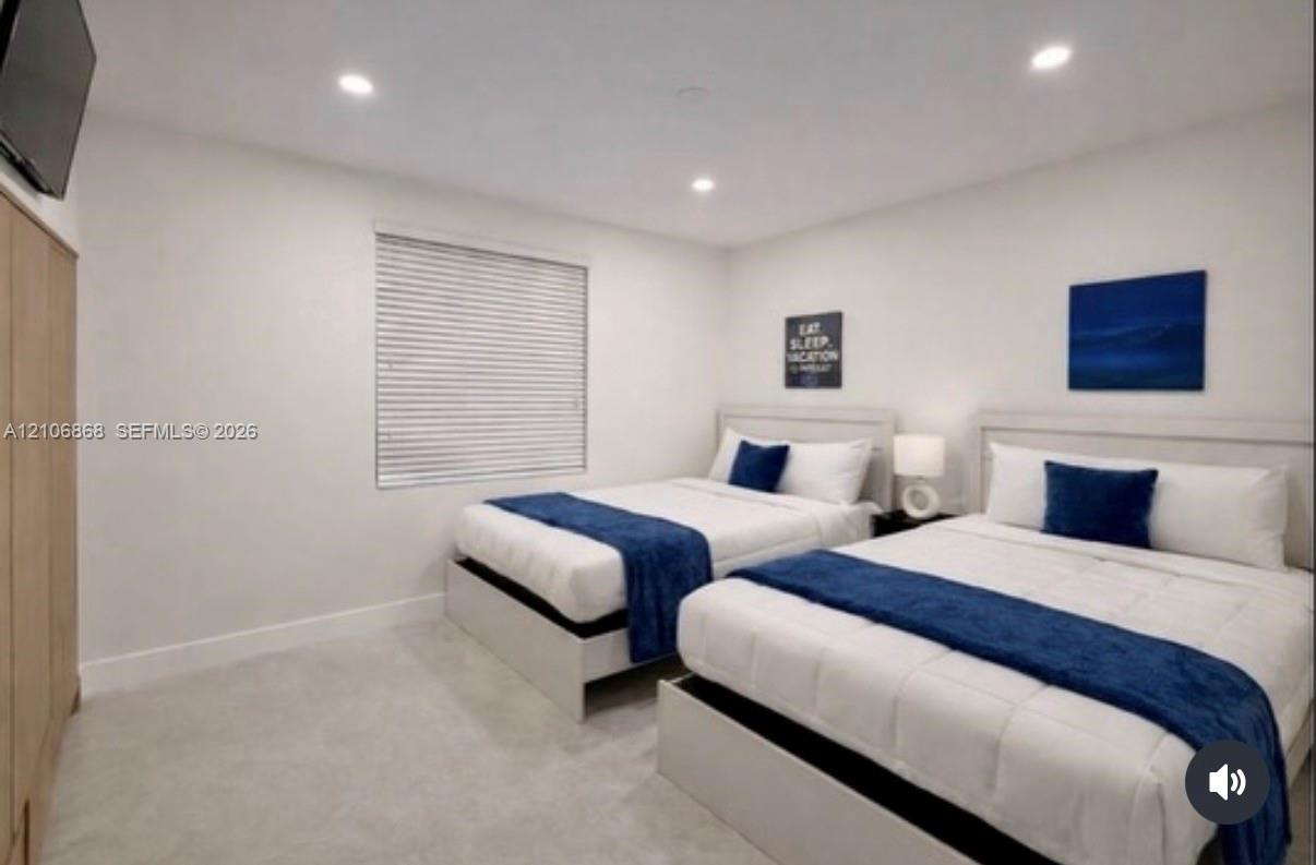 Neutral-toned carpeting, recessed lighting, and a window with horizontal blinds