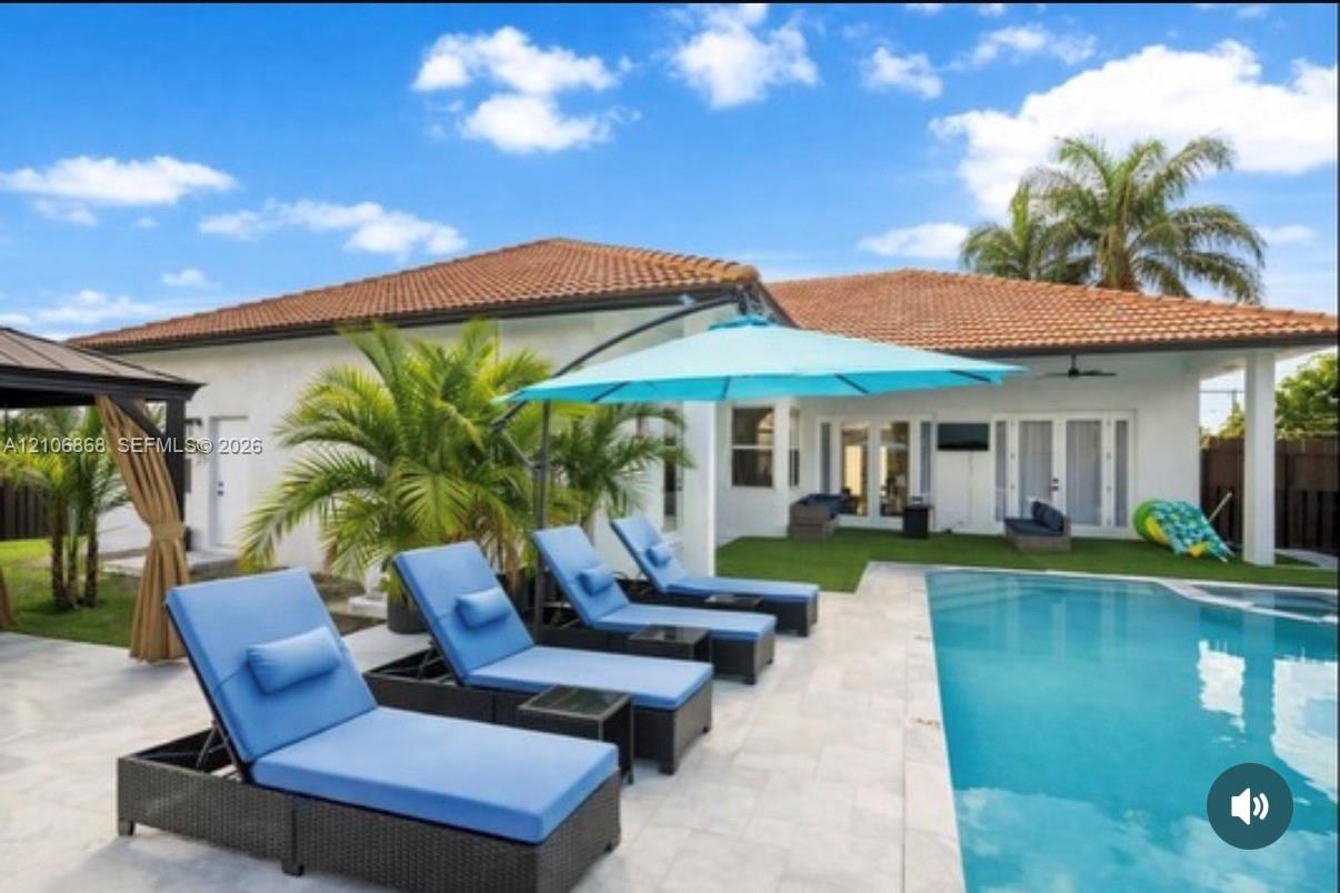 Rear exterior featuring a swimming pool, stone-finish patio, covered porch, and tile roof Rear exterior featuring a swimming pool, stone-finish patio, covered porch, and tile roof