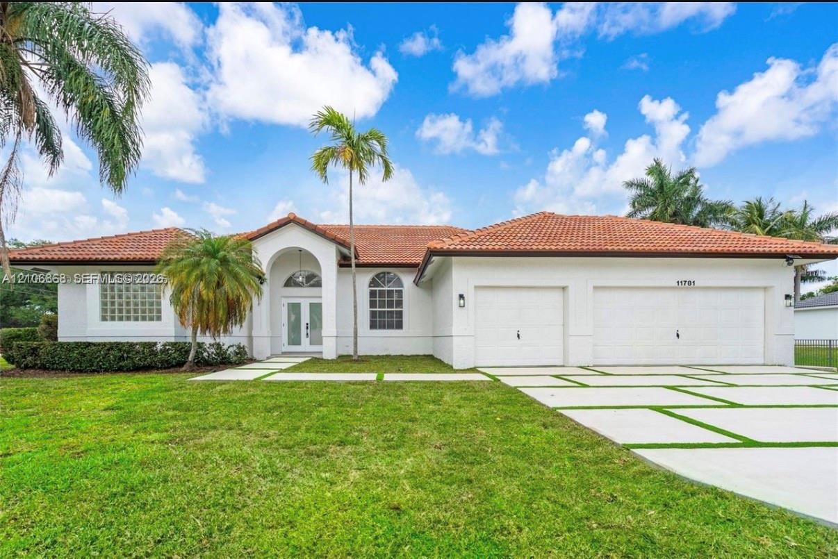 Single-story residence featuring a terracotta-tiled roof, white stucco exterior, arched entryway, arched transom windows, and a multi-car garage Single-story residence featuring a terracotta-tiled roof, white stucco exterior, arched entryway, arched transom windows, and a multi-car garage