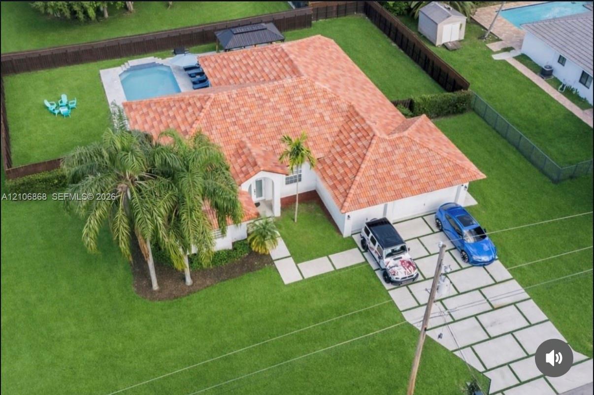 Tile roof residence featuring a concrete paver driveway, an in-ground swimming pool, a fully fenced backyard, and mature landscaping Tile roof residence featuring a concrete paver driveway, an in-ground swimming pool, a fully fenced backyard, and mature landscaping