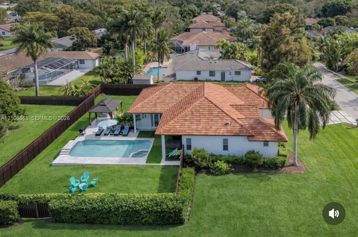 Single-story residence featuring a clay tile roof, an inground swimming pool with a stone paver deck, a detached gazebo, and expansive manicured lawn space enclosed by a privacy fence Single-story residence featuring a clay tile roof, an inground swimming pool with a stone paver deck, a detached gazebo, and expansive manicured lawn space enclosed by a privacy fence
