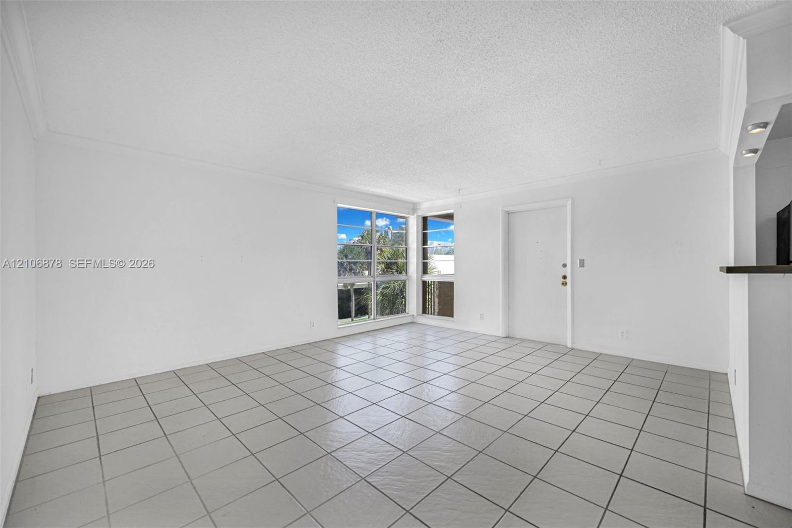 Neutral-toned ceramic tile flooring, corner window configuration, and recessed accent lighting over a pass-through opening