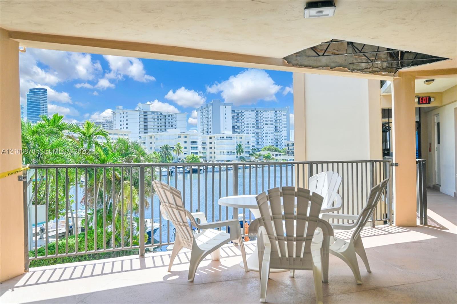 Covered balcony featuring metal railings and concrete flooring with water and city skyline surroundings