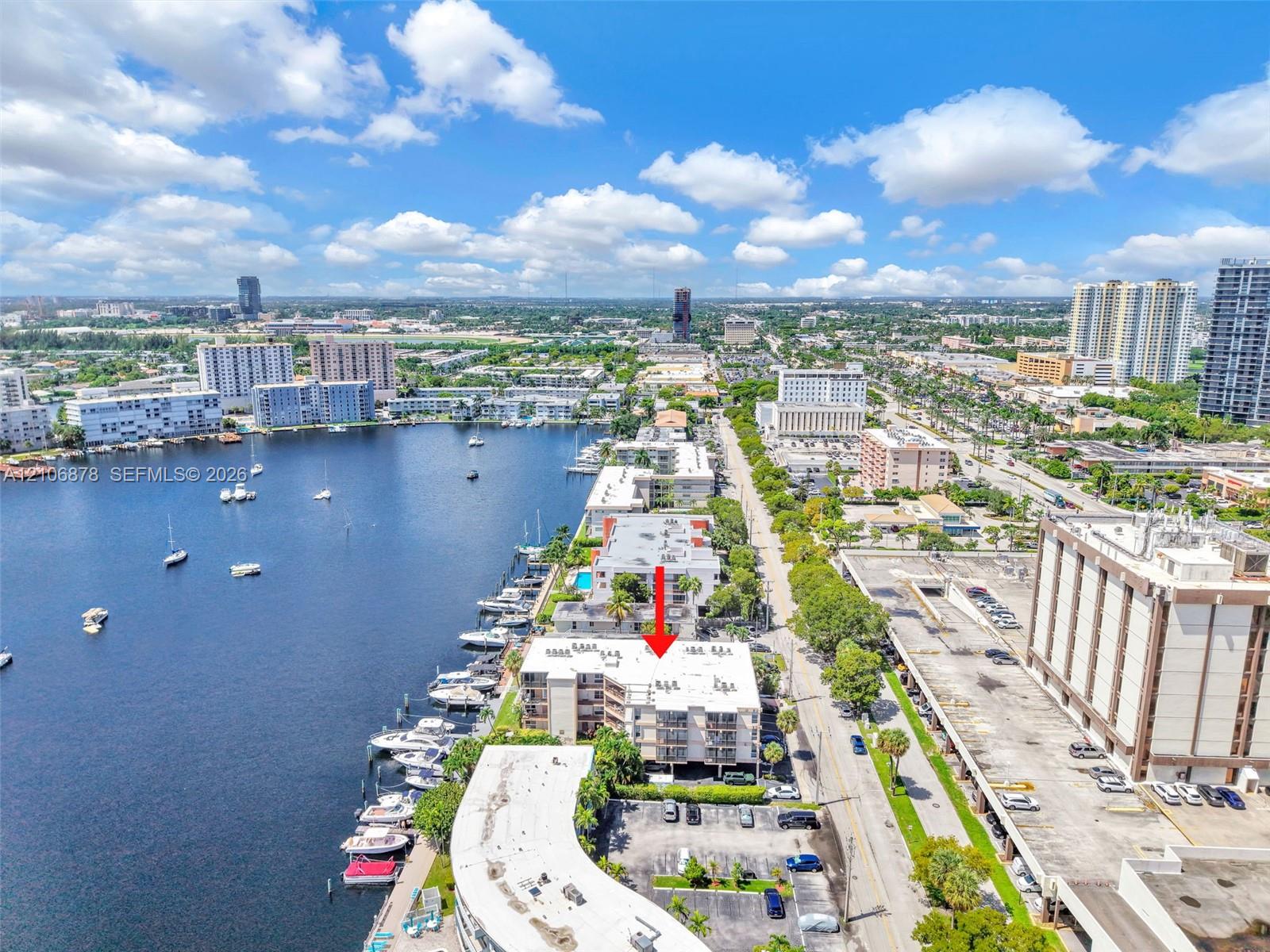Waterfront mid-rise building featuring private boat slips, multi-level balconies, surface parking, and direct access to navigable waterways