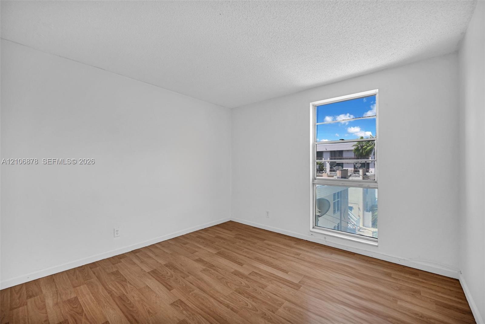 Interior space featuring wood-finish flooring, white walls, and a multi-pane window