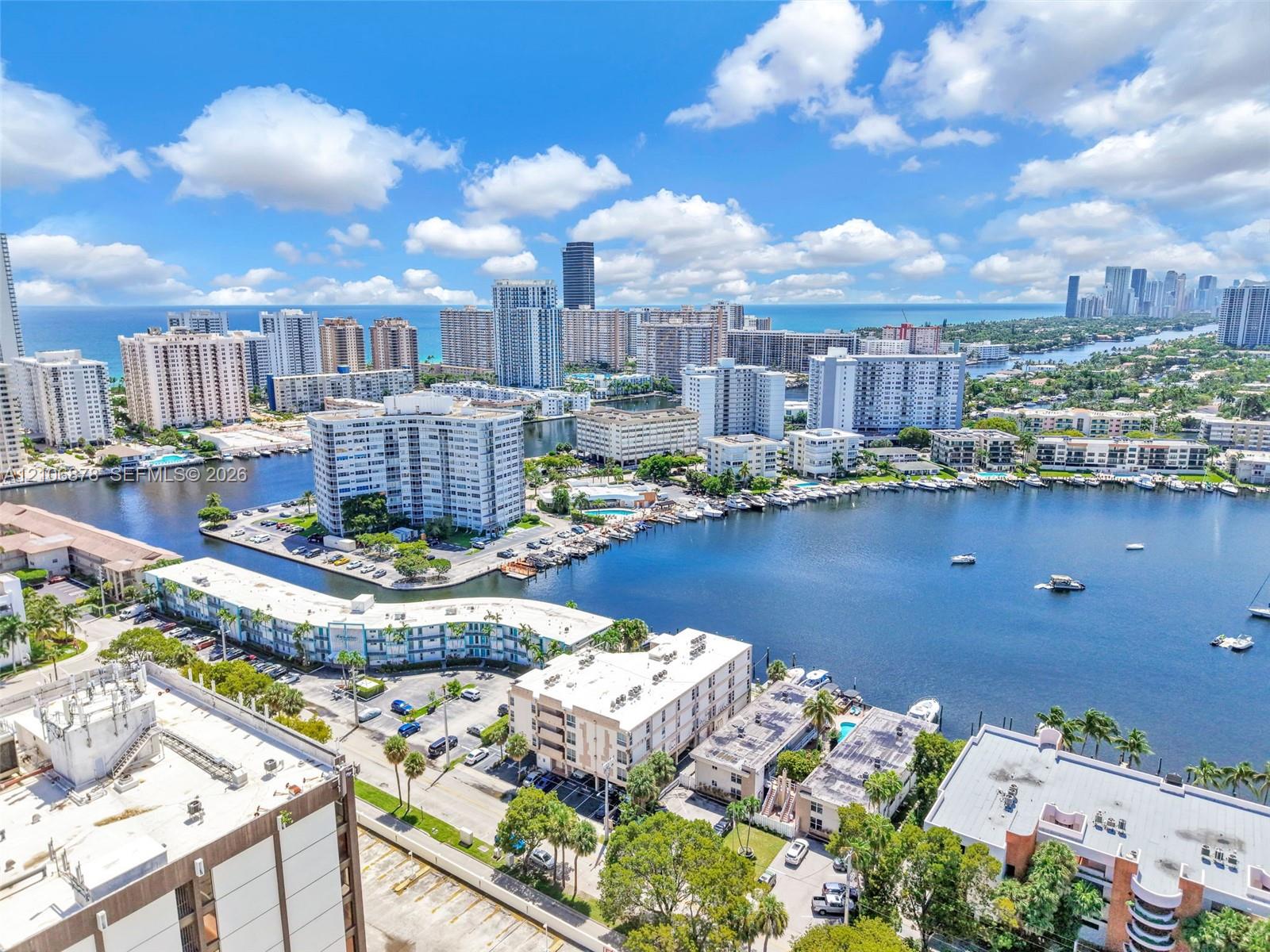 Aerial perspective of a waterfront setting featuring an expansive waterway, multiple boat slips, mature palm trees, and dense urban skyline