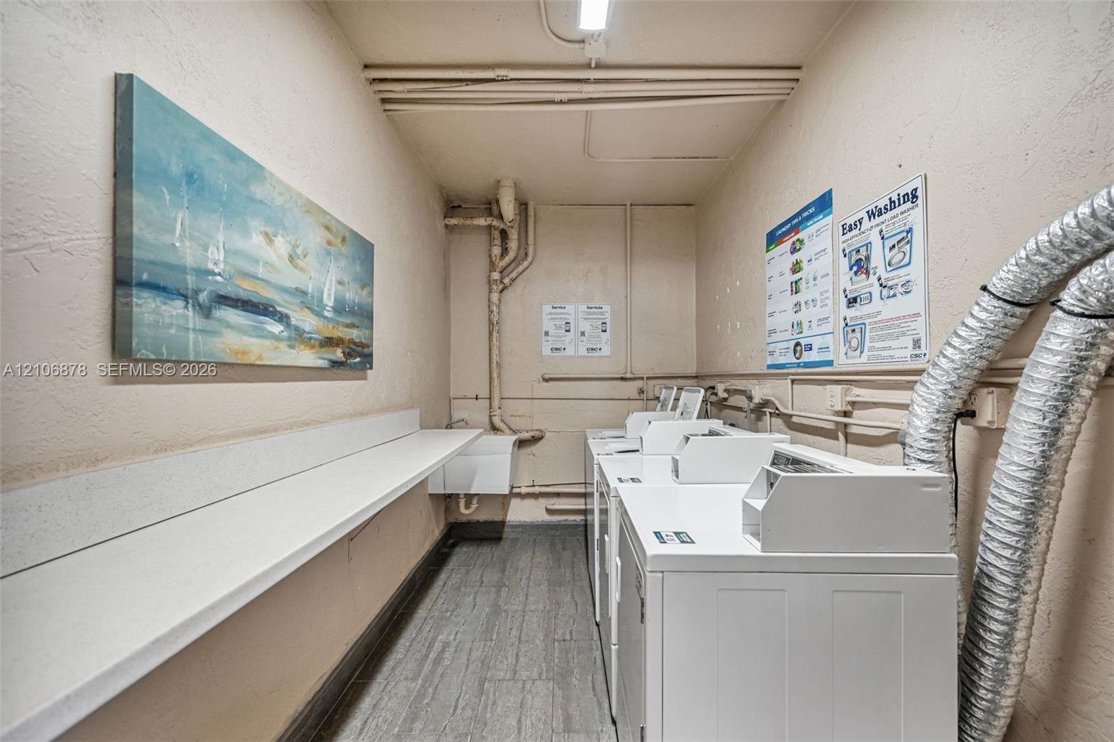 Laundry area featuring wood-finish flooring, a white countertop surface, and a wall-mounted utility sink