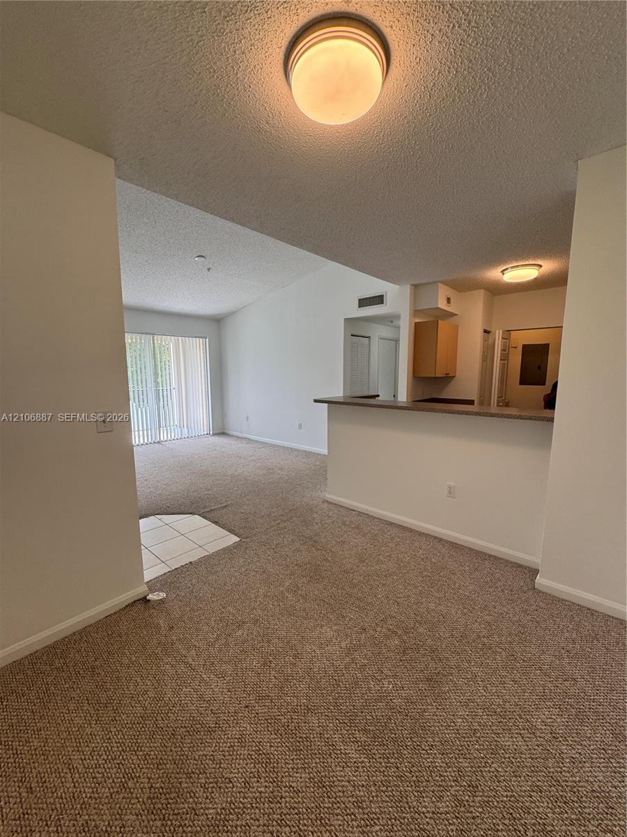 Interior featuring wall-to-wall carpeting, breakfast bar with countertop, sliding glass door, and flush-mount ceiling lighting