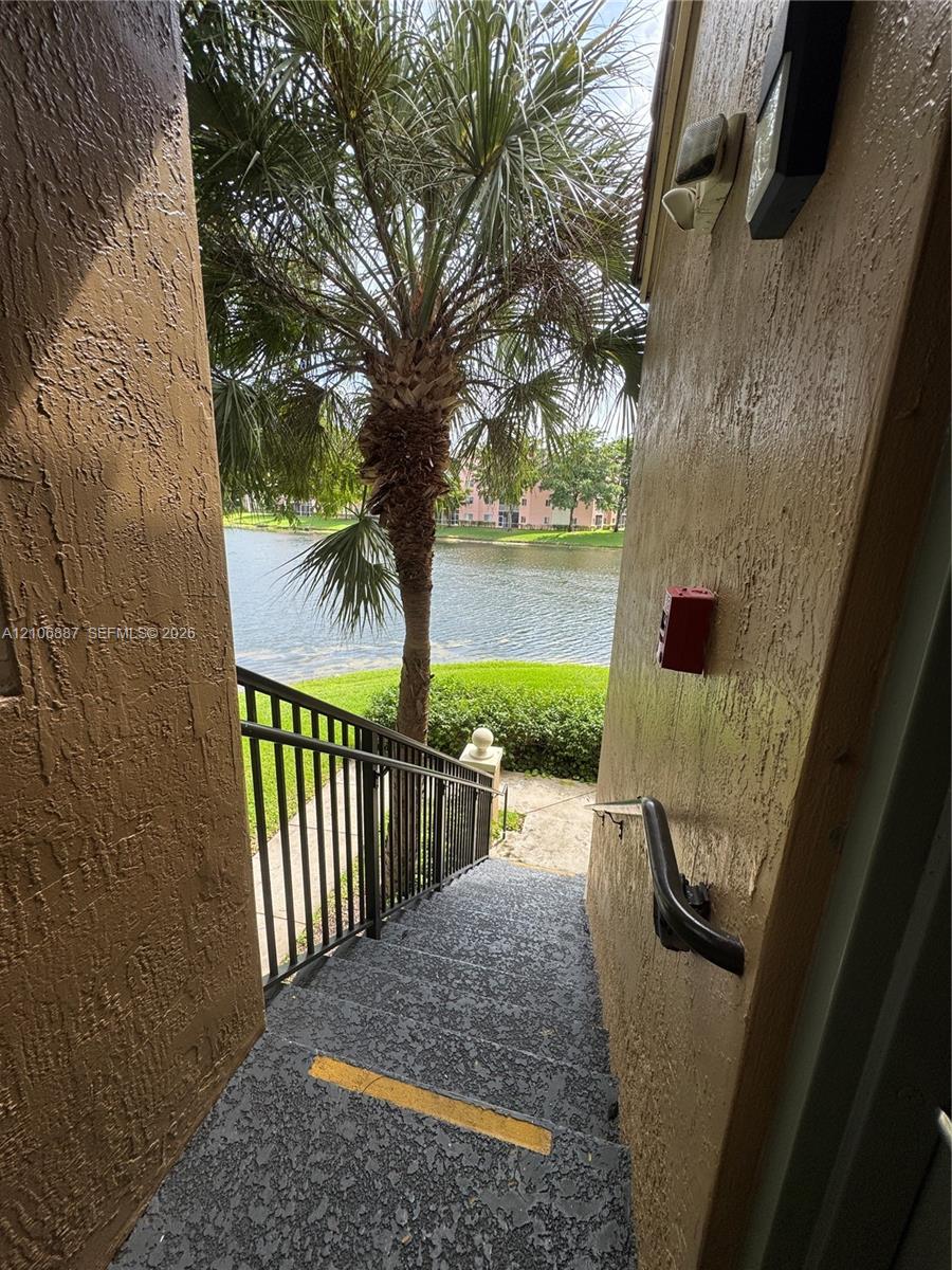 Exterior staircase featuring textured concrete steps, black metal handrails, and a water-facing orientation