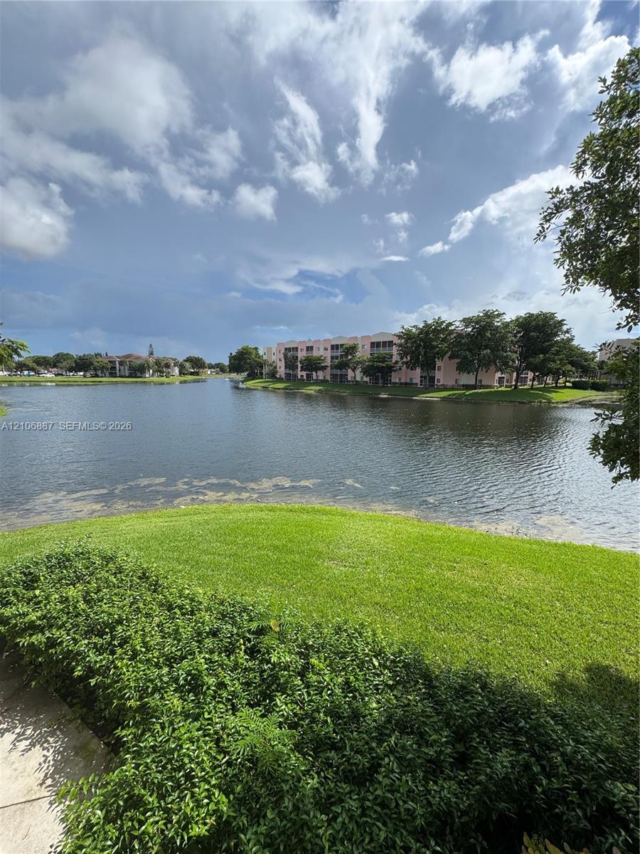 Waterfront scenery featuring a expansive lake, manicured lawn, and mature greenery