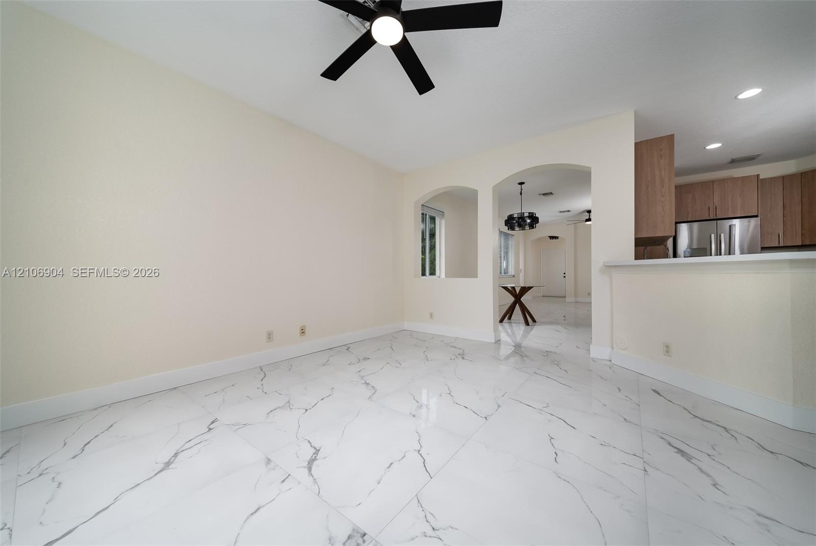 Large-format polished tile flooring featuring a veined pattern, recessed lighting, architectural arched cutouts, and a ceiling-mounted fan with integrated lighting