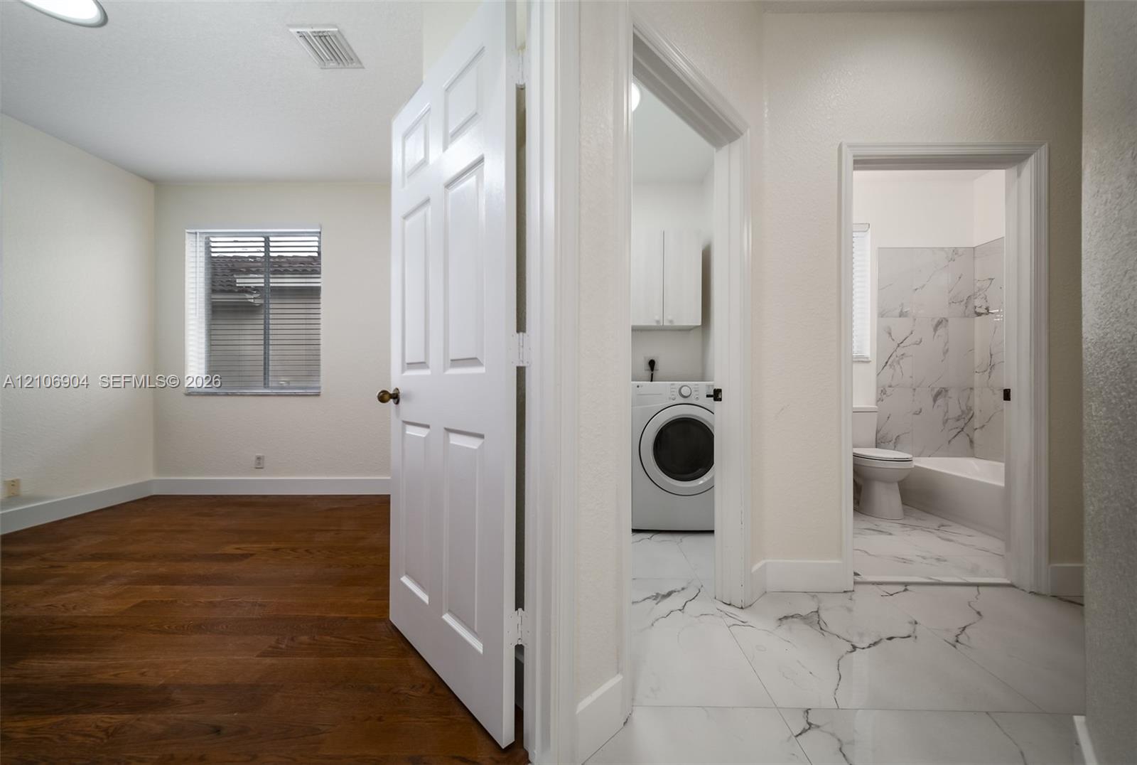 Interior featuring wood-finish flooring, large-format tile flooring, six-panel doors, and a tiled shower surround