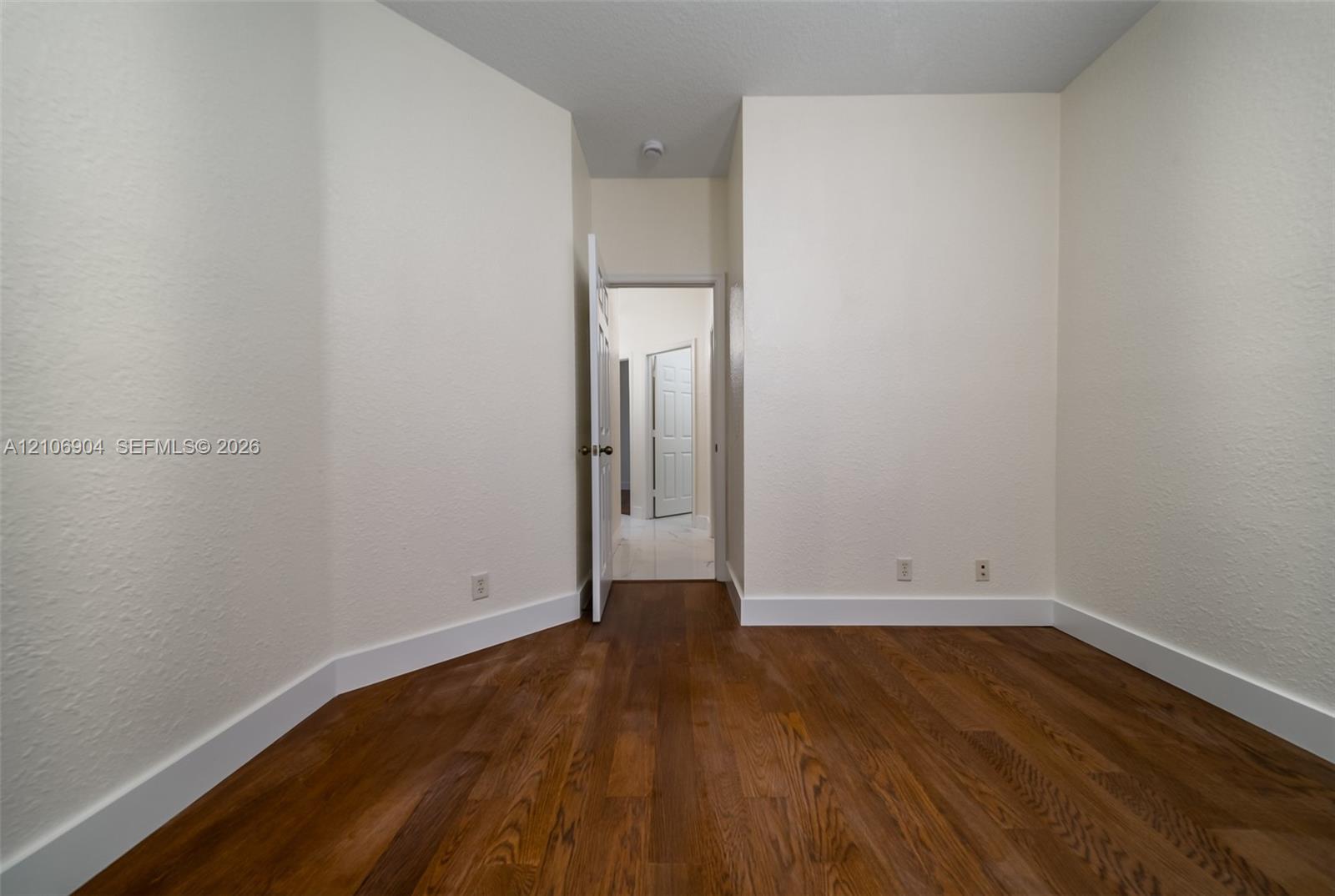 Room featuring wood-finish flooring, textured walls, and paneled interior doors