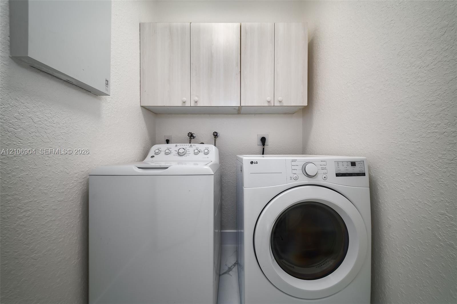 Laundry area featuring light-finish wood cabinetry and wall-mounted storage unit