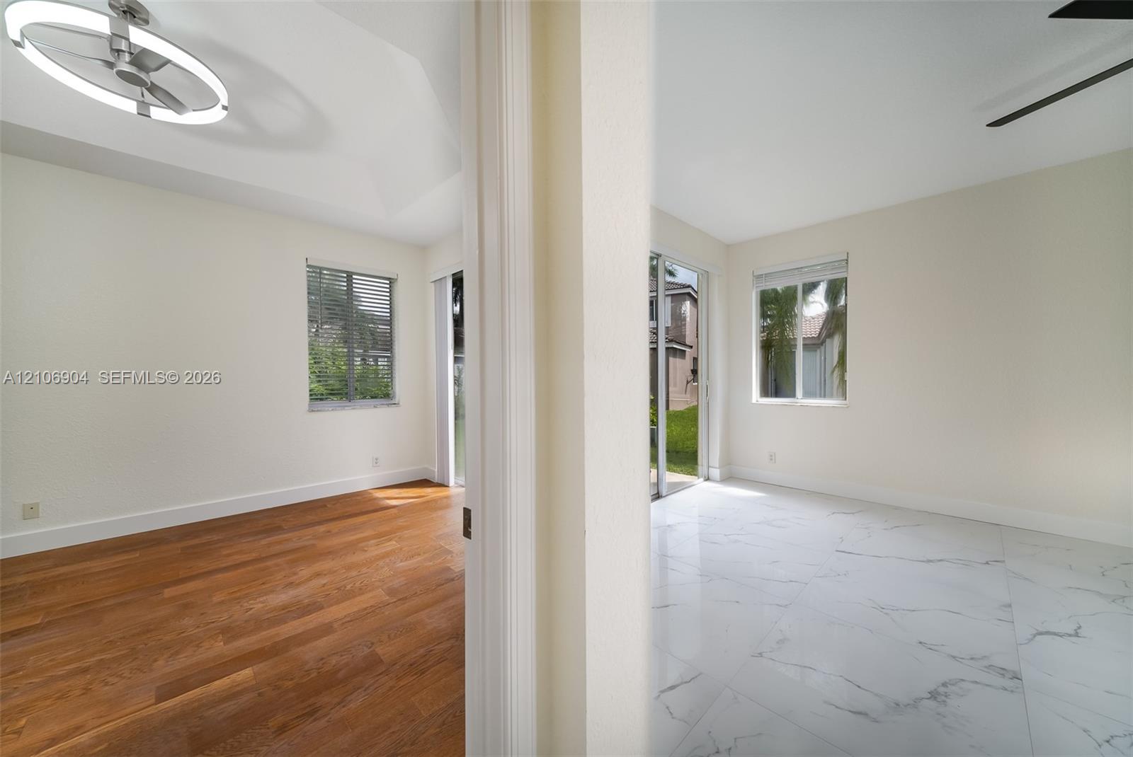 Interior space featuring vaulted ceilings, wood-finish flooring, large-format tile flooring, a contemporary circular LED chandelier, and sliding glass doors
