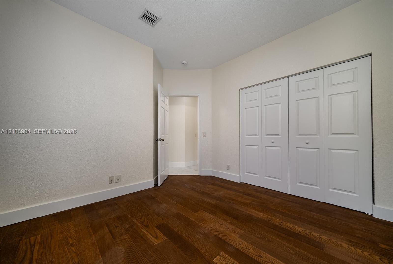 Wood-finish flooring, neutral wall tones, and built-in closet with six-panel doors