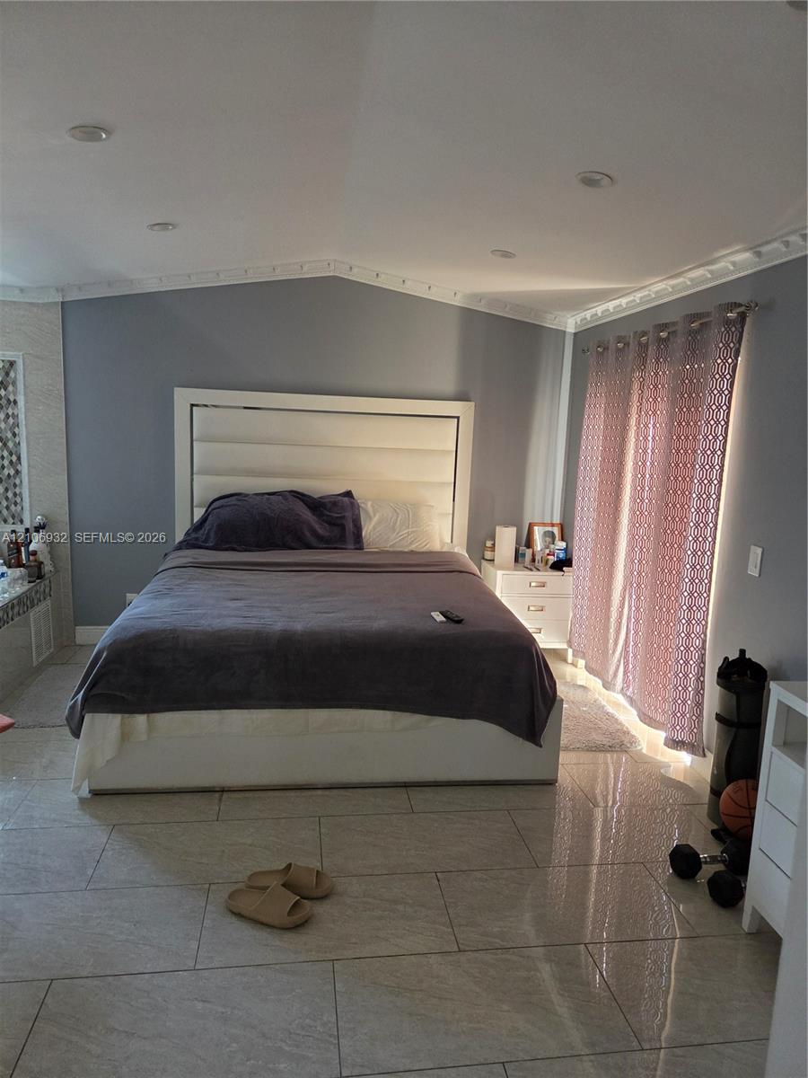 Vaulted ceilings with crown molding, large-format tile flooring, and recessed lighting