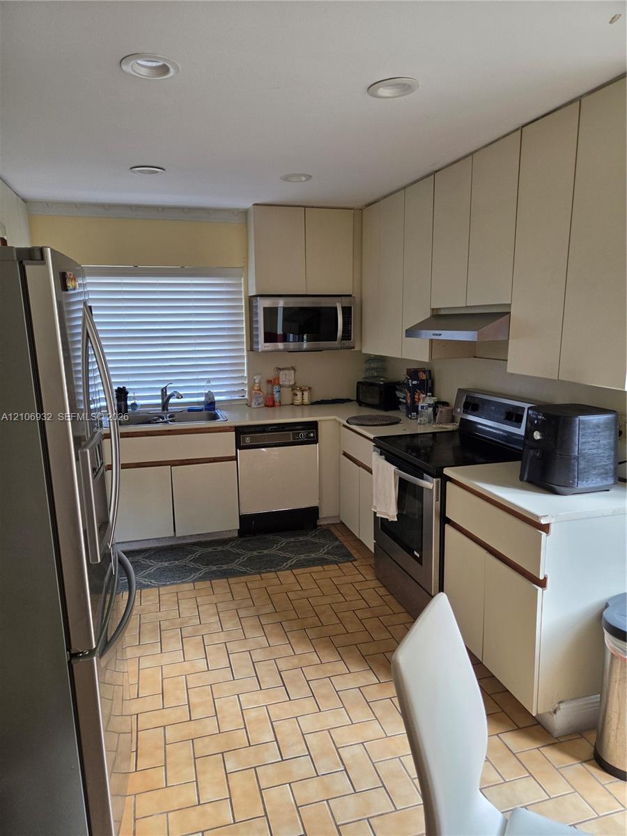 Kitchen featuring flat-panel cabinetry, stainless steel appliances, recessed ceiling lighting, and ceramic tile flooring in a herringbone pattern