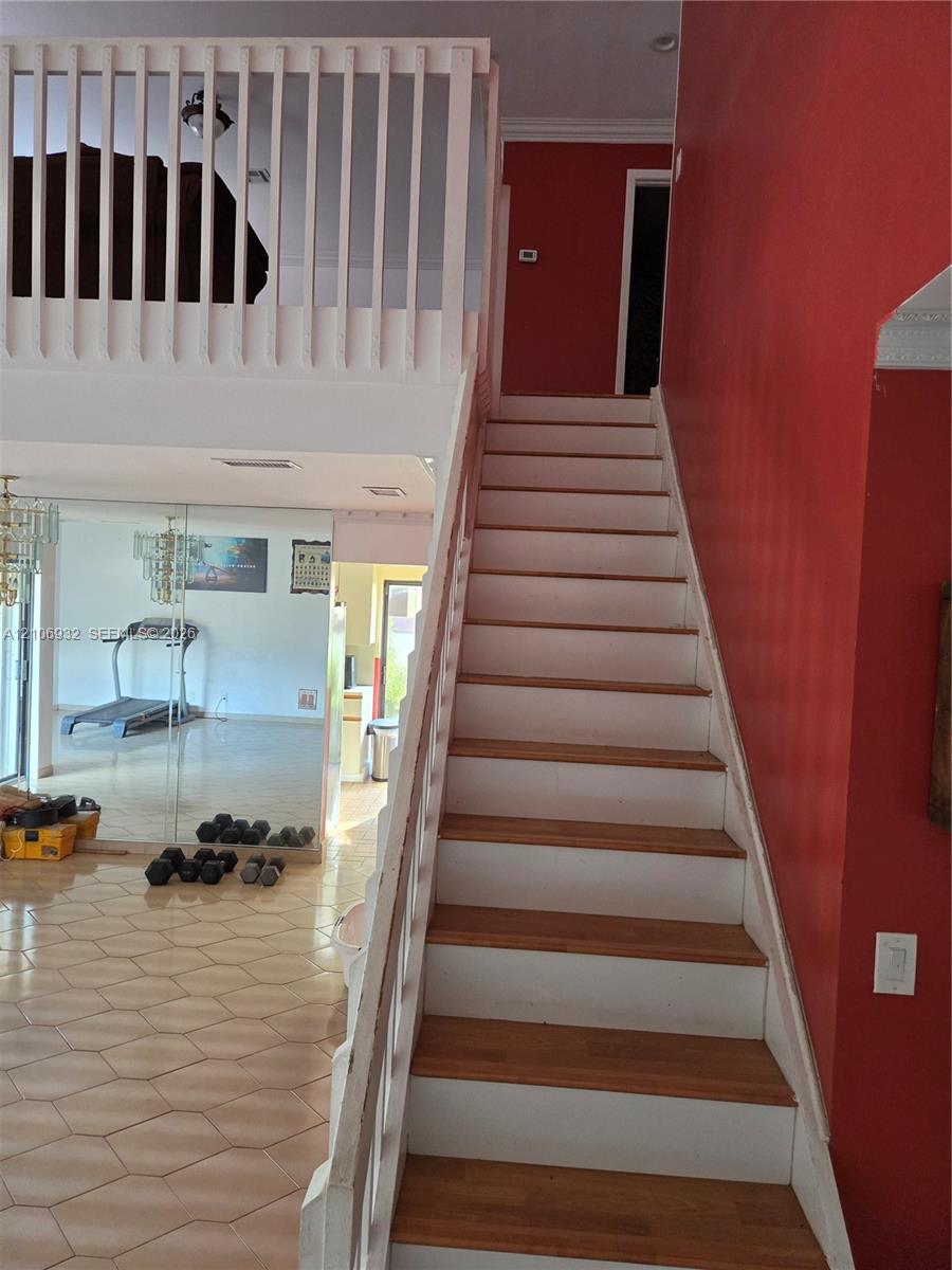 Staircase featuring wood treads and painted risers, complemented by a white balustrade and mezzanine railing