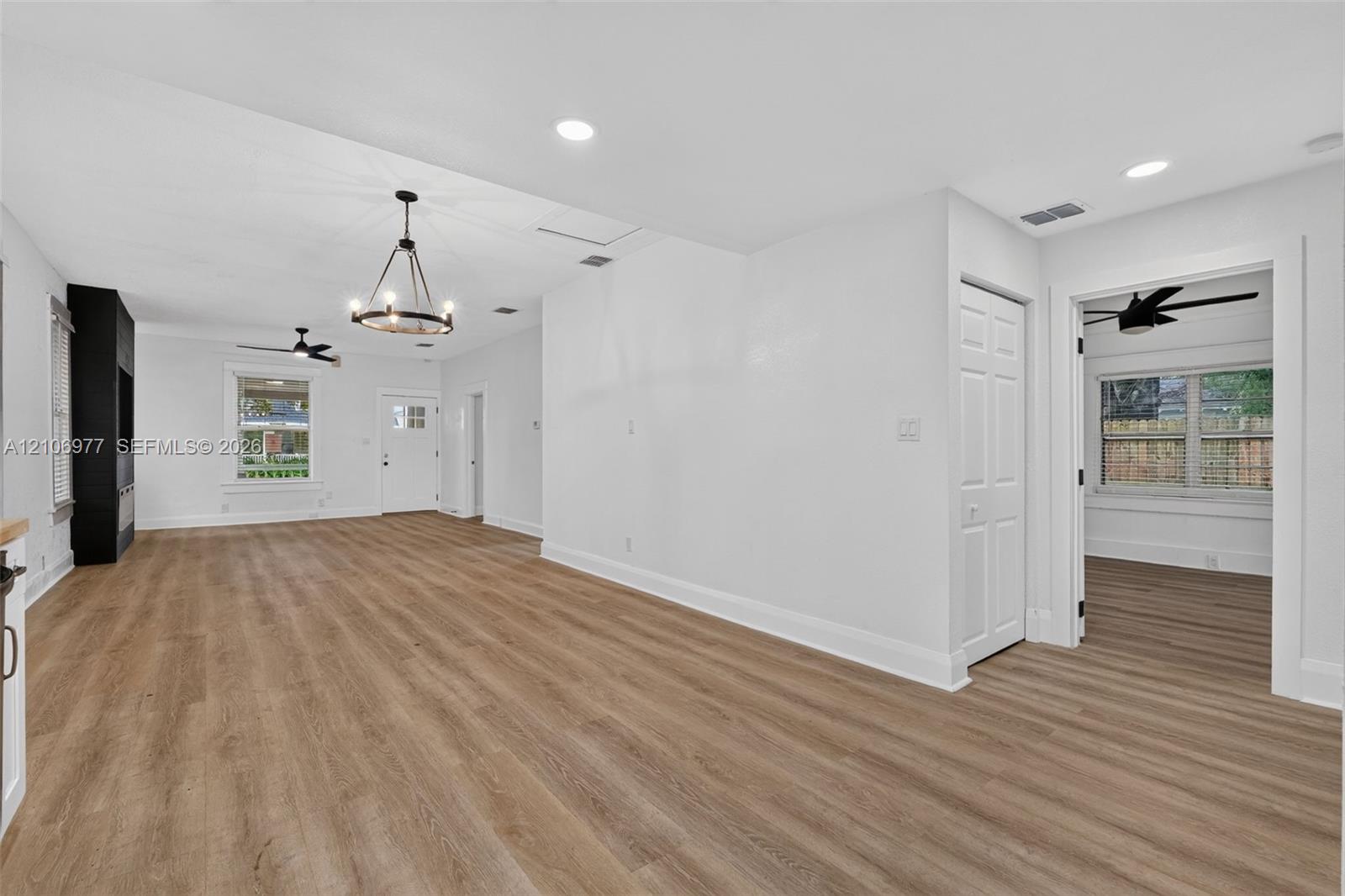 Open-concept interior featuring wood-finish flooring, recessed lighting, a modern chandelier, and built-in black cabinetry
