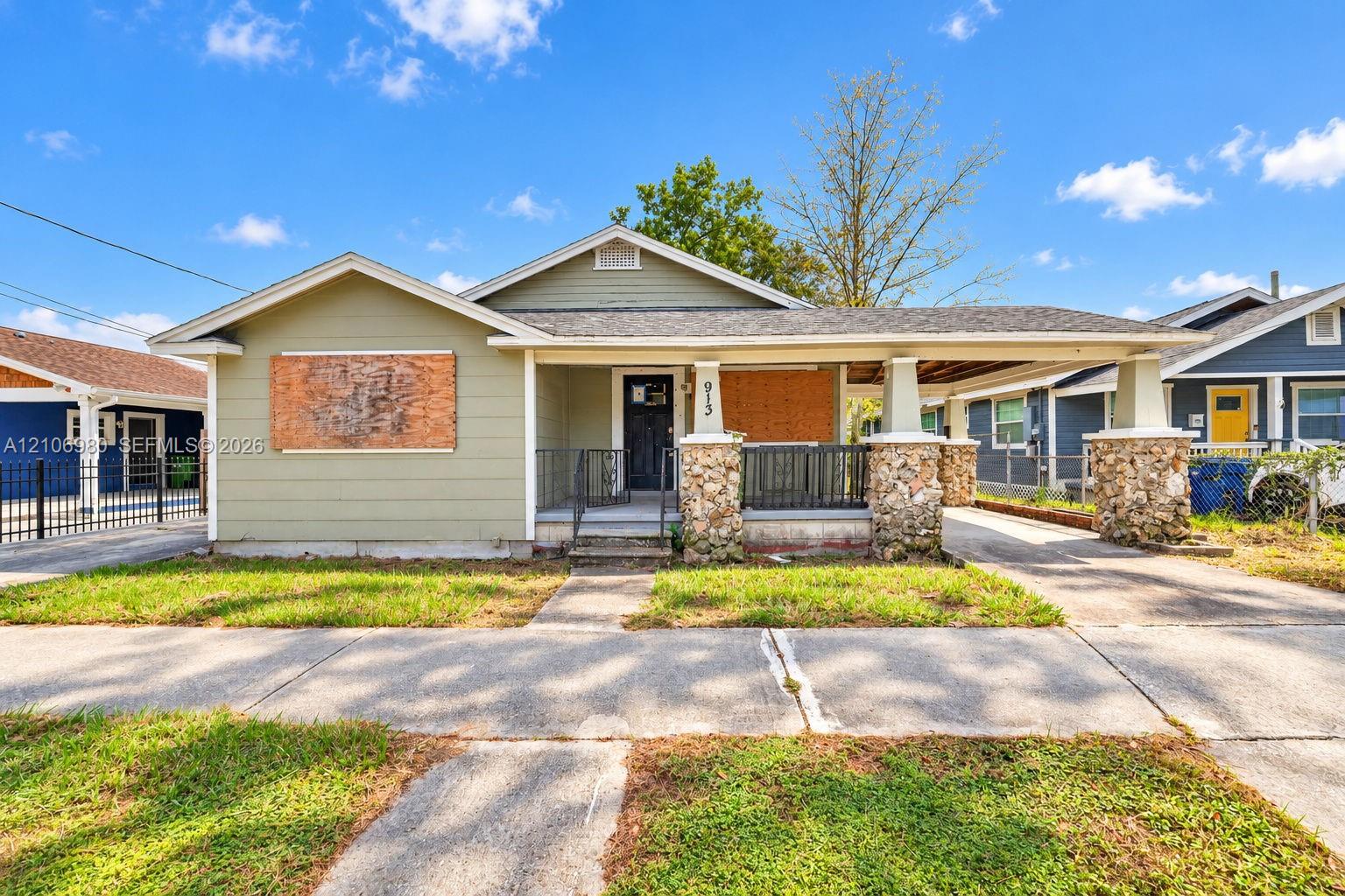 Craftsman-style bungalow exterior featuring lap siding, an expansive front porch with stone-clad columns, and a detached carport