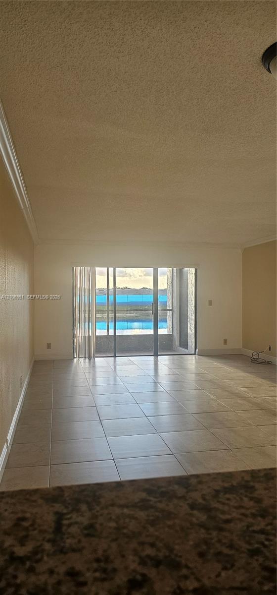 Interior space featuring large-format neutral tile flooring and sliding glass doors leading to an exterior balcony Interior space featuring large-format neutral tile flooring and sliding glass doors leading to an exterior balcony