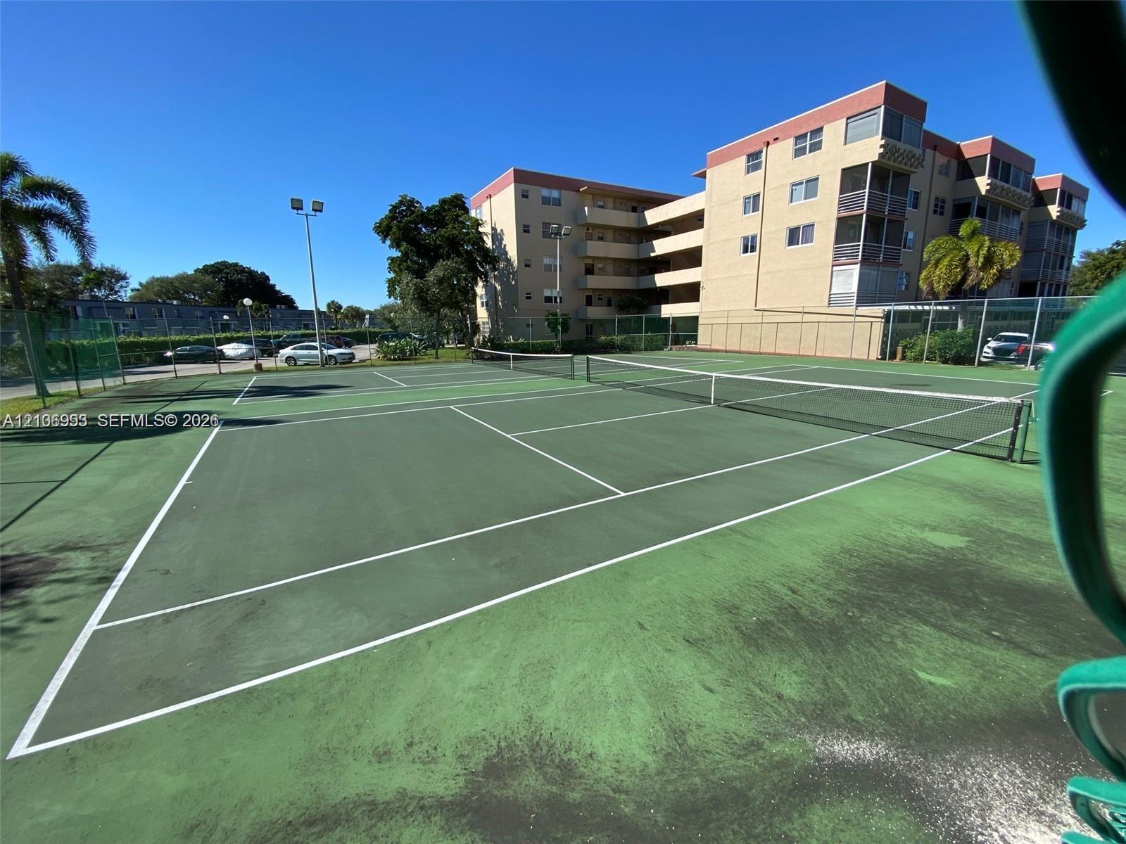 Tennis court featuring a hard surface, perimeter fencing, and dual net systems