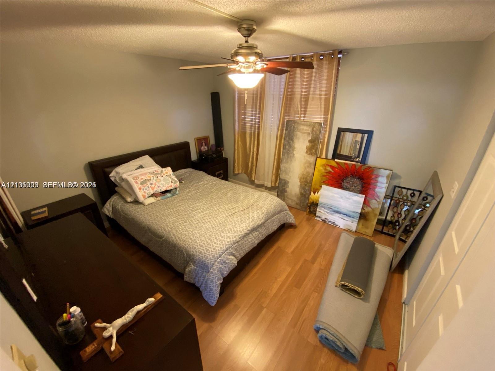 Wood-finish flooring, ceiling fan with integrated lighting, and multi-panel closet doors