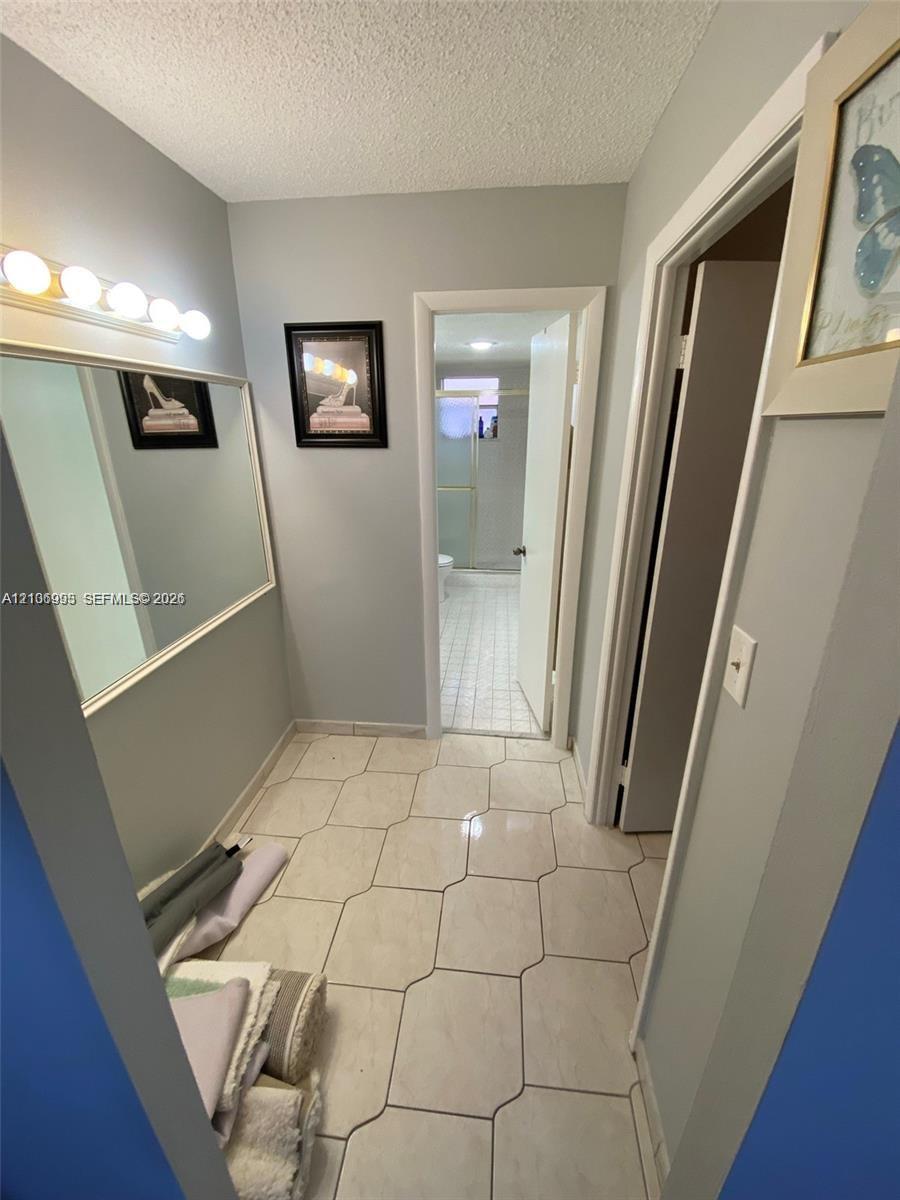 Wall-mounted mirror with a five-light vanity fixture and large-format ceramic tile flooring