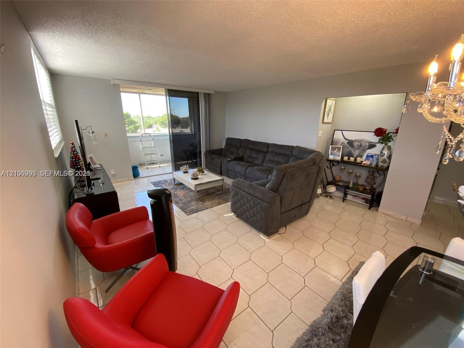 Living area featuring hexagonal tile flooring, decorative chandelier, and sliding glass door access to an exterior balcony