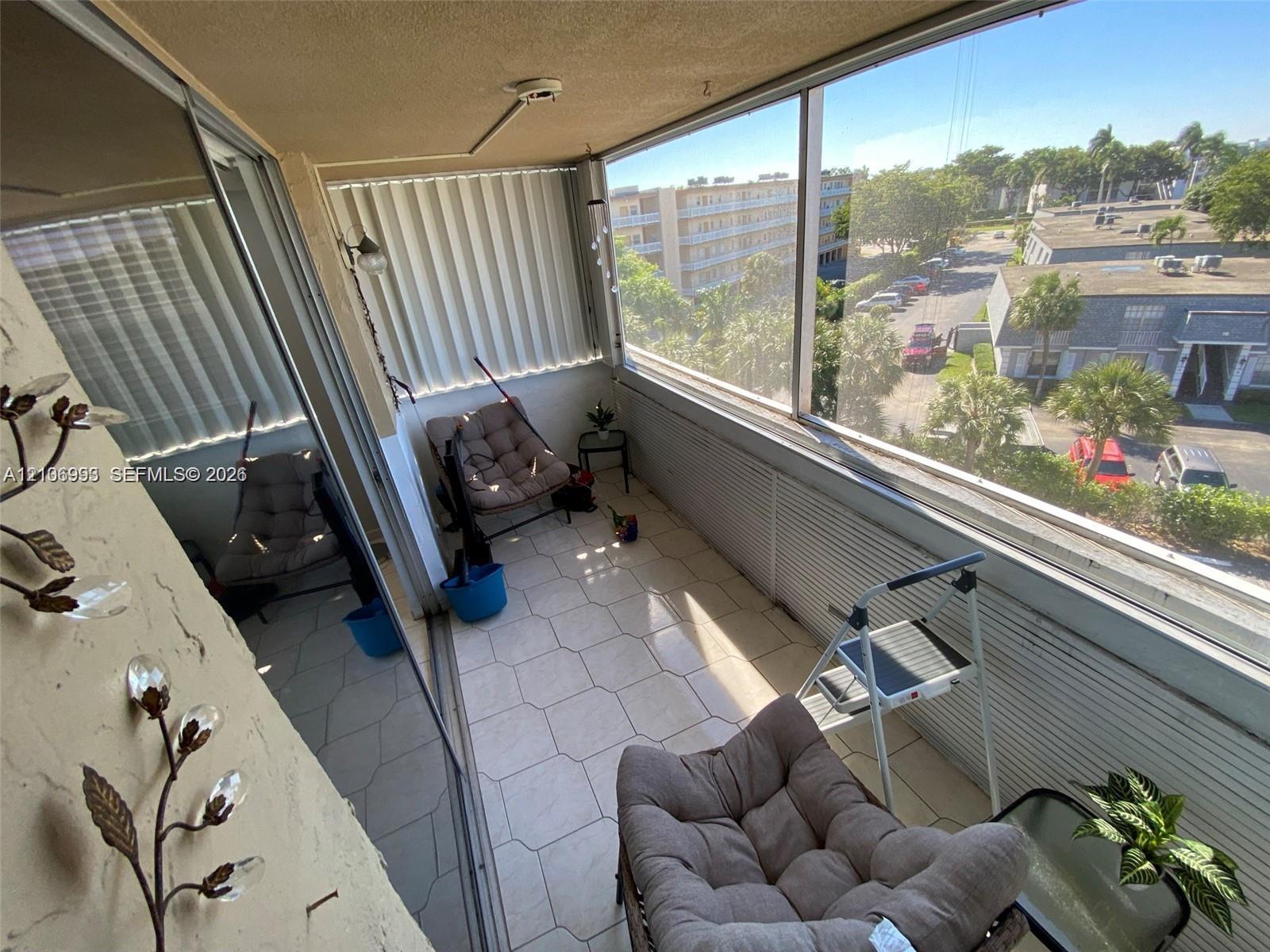 Enclosed balcony featuring tile flooring, floor-to-ceiling glass paneling, and sliding windows