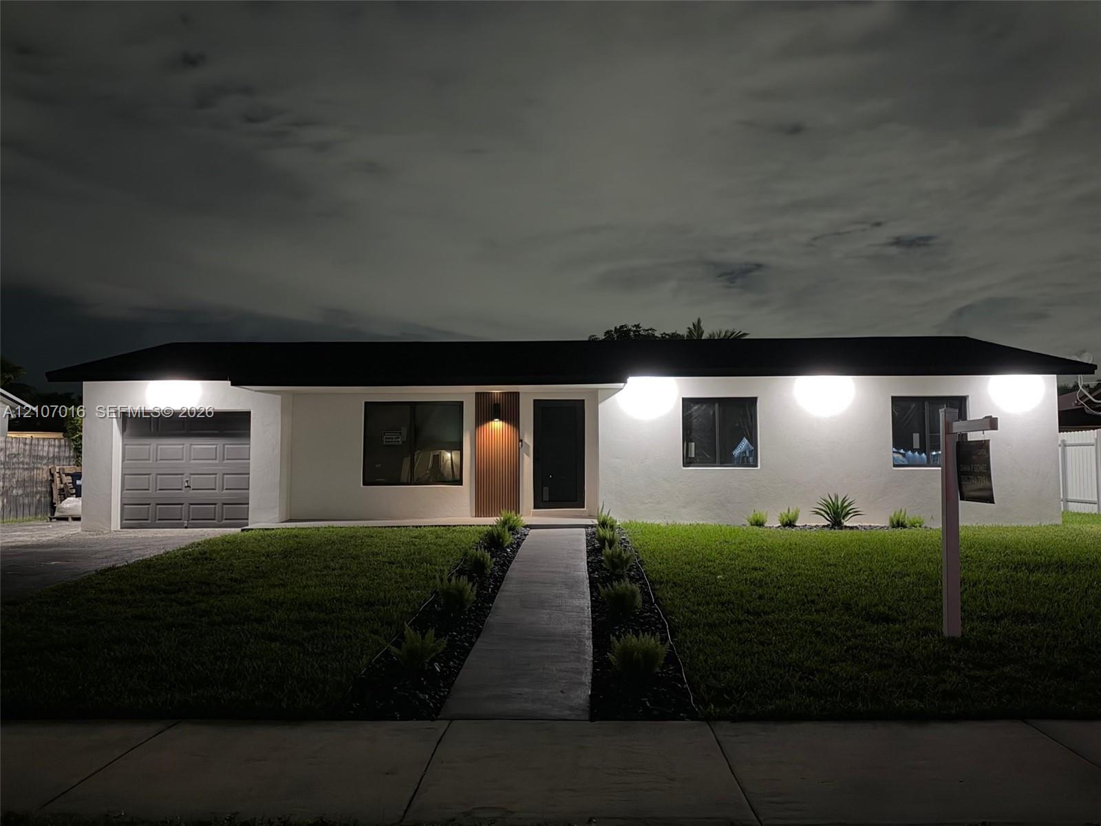 Single-story exterior featuring a smooth stucco finish, a one-car garage, and a straight concrete walkway lined with landscaping beds