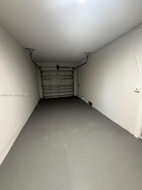 Enclosed space featuring a painted concrete floor, neutral wall finishes, and a sectional metal garage door