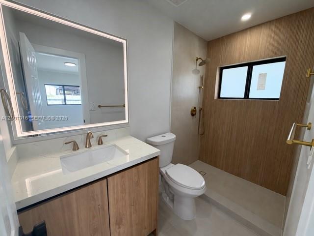 Bathroom featuring a wood-finish vanity with a stone-surface countertop, an integrated LED-lit vanity mirror, a walk-in shower with wood-finish tile accents, and brushed gold-tone fixtures