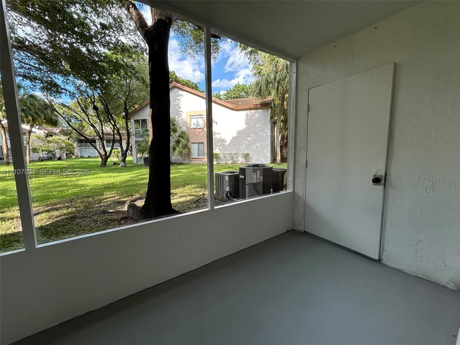Screened-in enclosure featuring concrete flooring, a solid-core utility door, and wide-span mesh screening