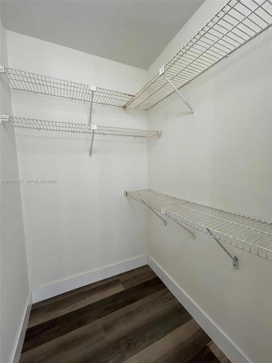 Storage space featuring multi-level white wire shelving and wood-finish flooring