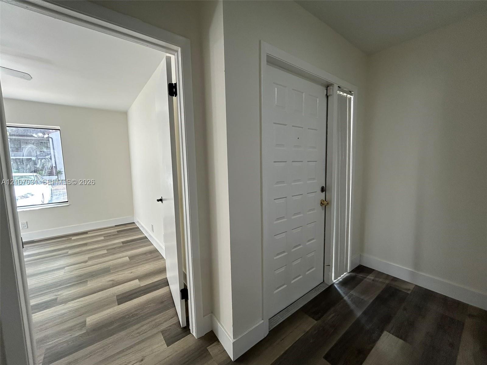 Entryway featuring wood-finish flooring, a multi-panel door with brass-finish hardware, and a vertical sidelight window
