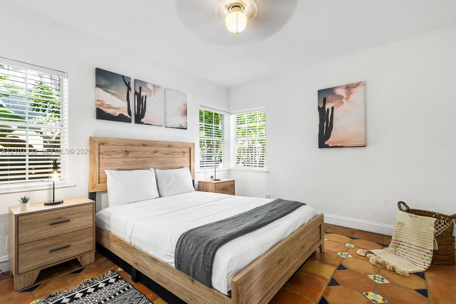 Room featuring terracotta tile flooring with inset decorative accents, multiple windows with horizontal blinds, and a central ceiling light fixture