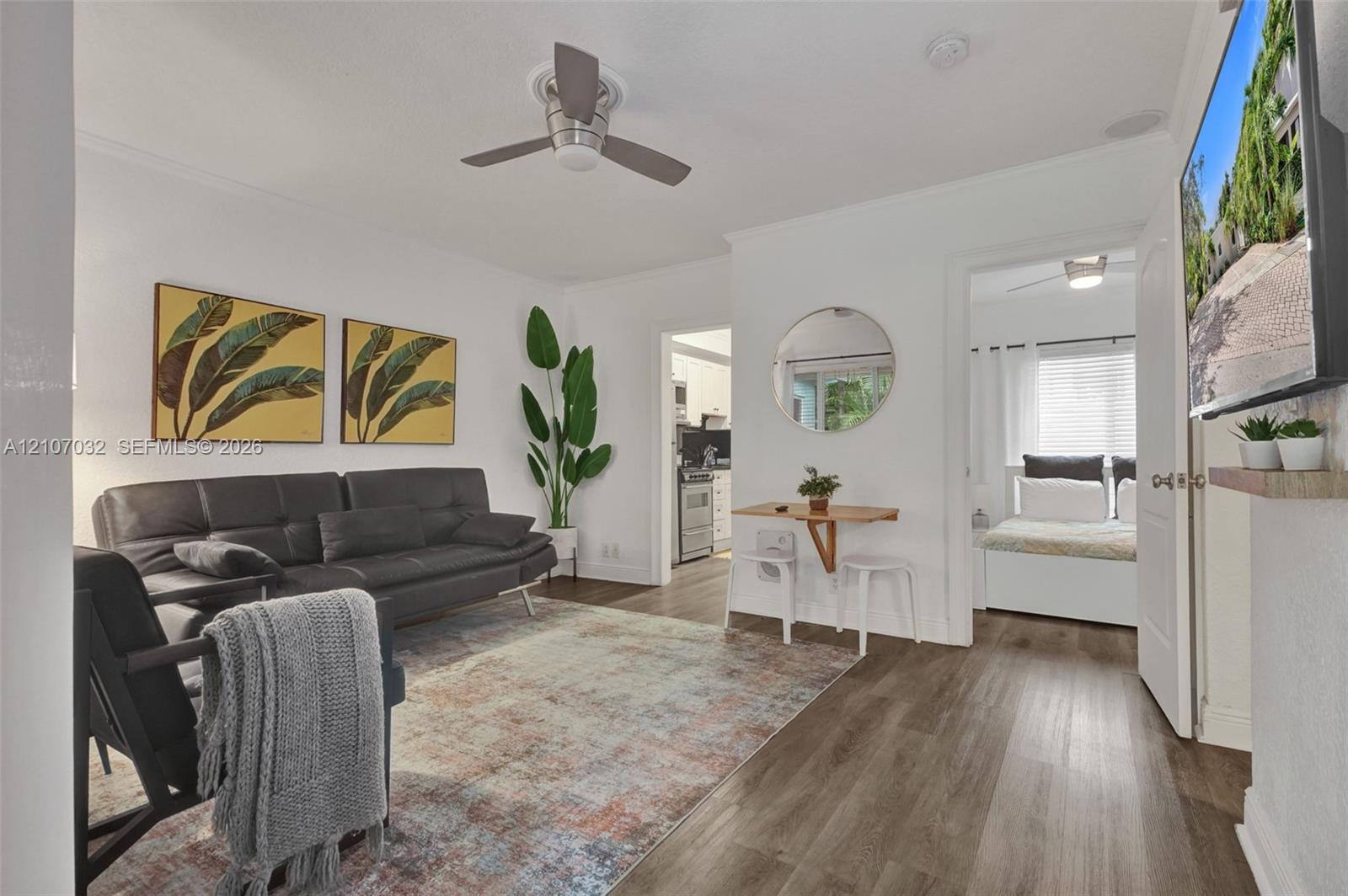Living space featuring wood-finish flooring, a ceiling fan, and a wall-mounted television shelf